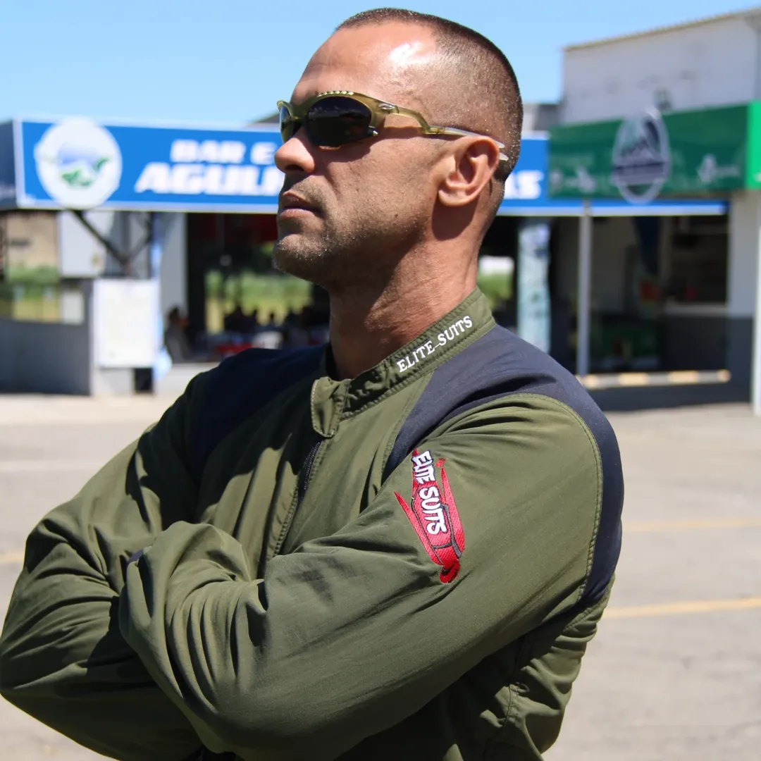 Paraquedista de braços cruzados com macacão Elite Suits verde